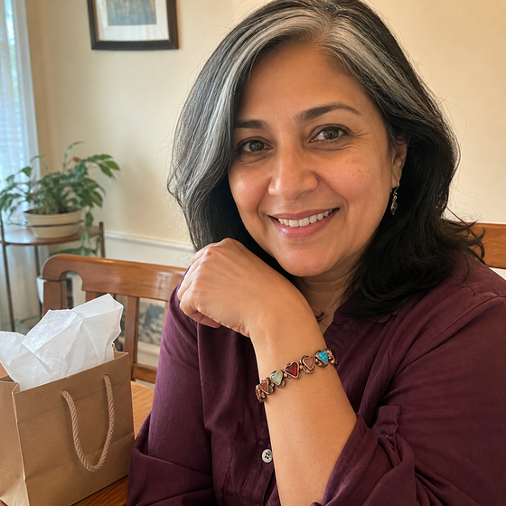 South Asian woman wearing the Aura bracelet beside a gift bag