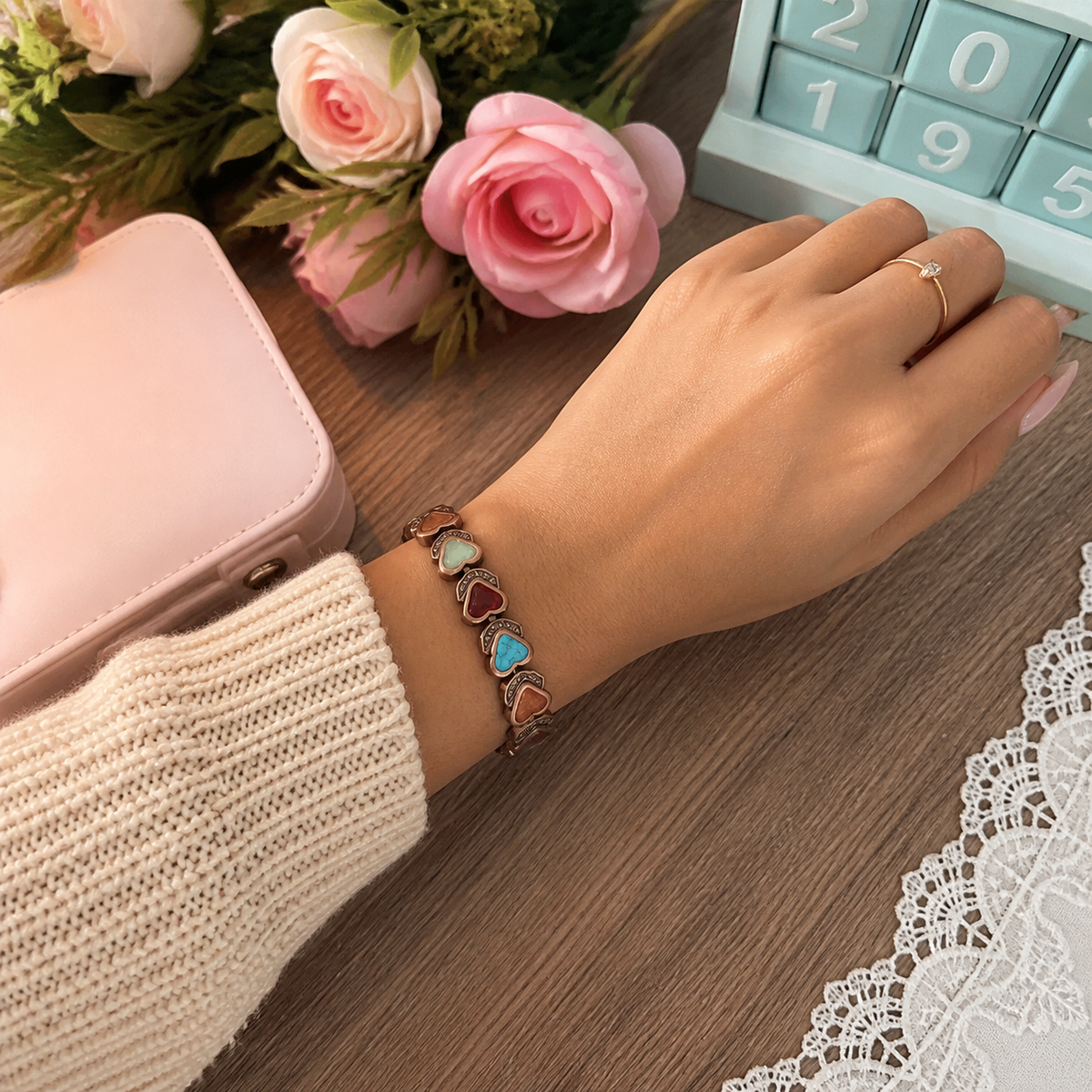 Aura bracelet styled with a cream knit sleeve at a pastel desk
