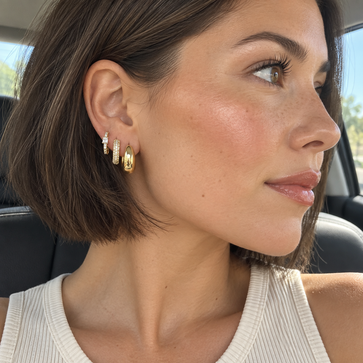 Woman wearing the three-piece Gold Tone chunky hoop earring stack in a car