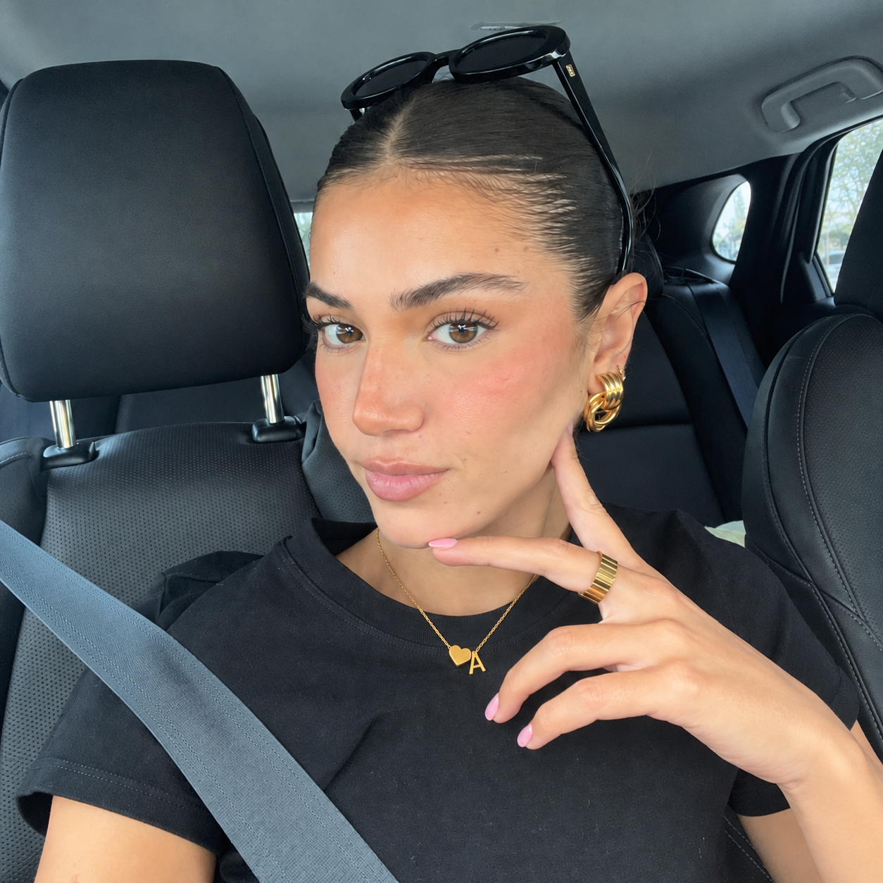 Woman in a black tee wearing a heart and initial necklace