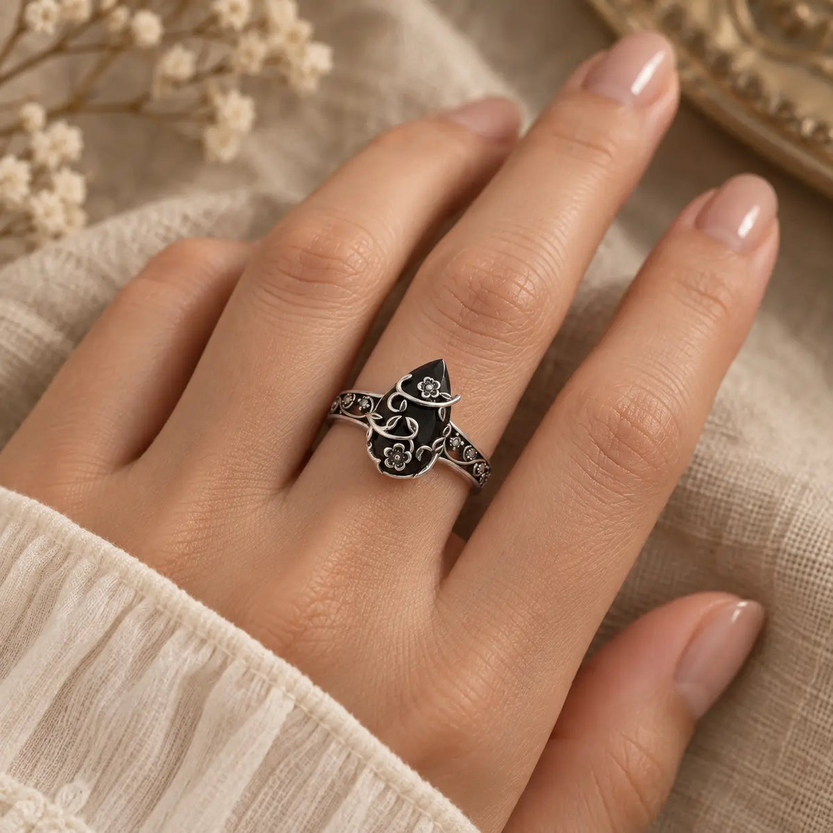 Exact on-hand view of the black teardrop flower ring