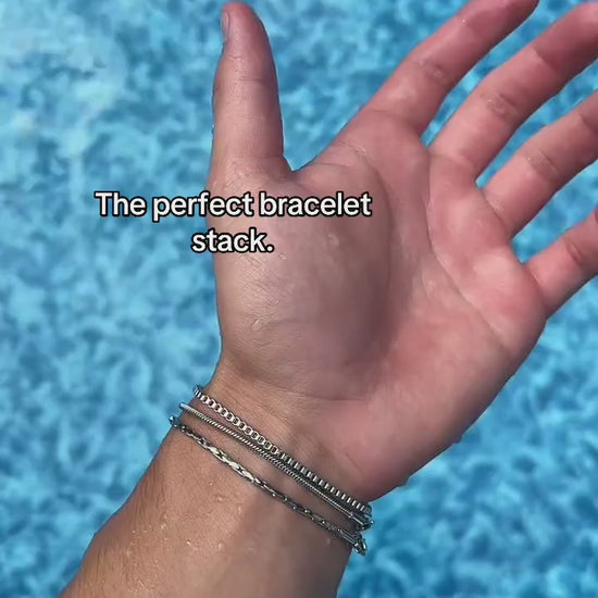 Three-chain Veyron bracelet stack shown on a wrist over blue pool water