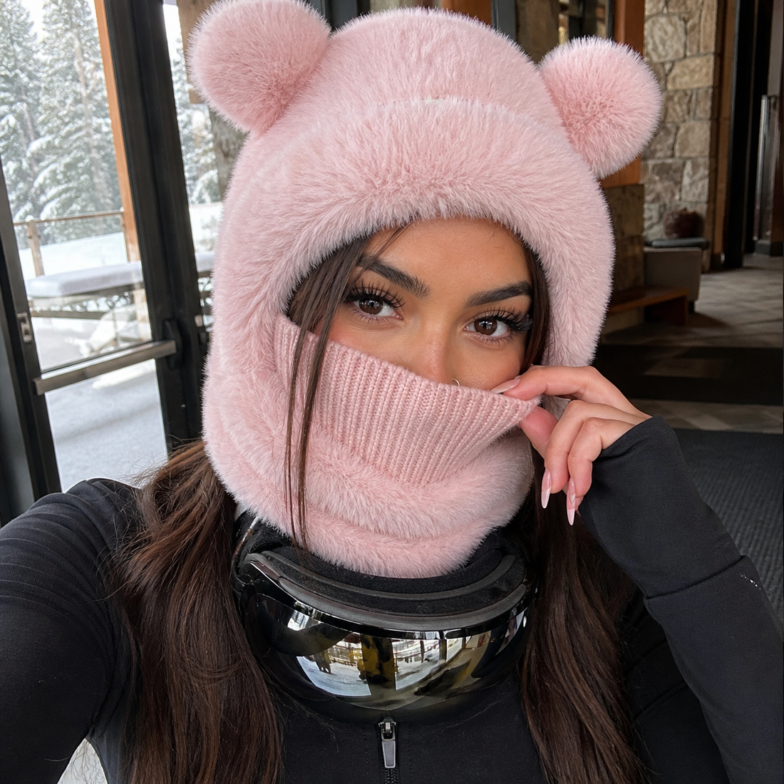 Latina woman styling the pink Teddy Bear Balaclava at a ski lodge